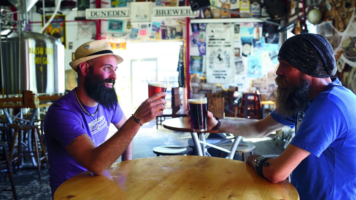 Two man toasting with beer inside of Dunedin Brewery.