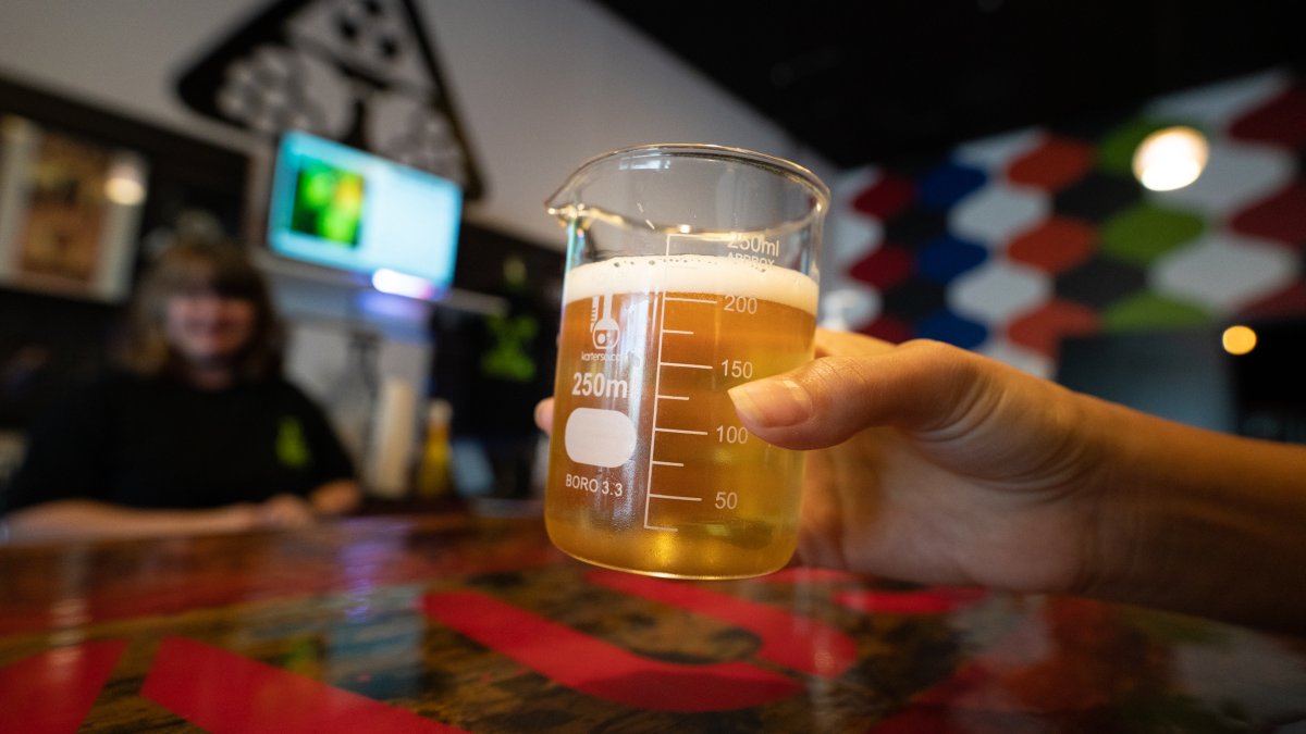 A person showing a lab glass with beer.