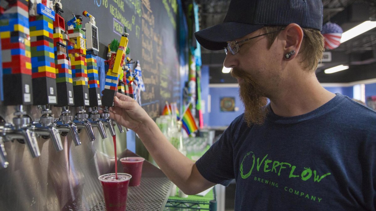 A man pouring a red beer from the Lego-looking beer taps.