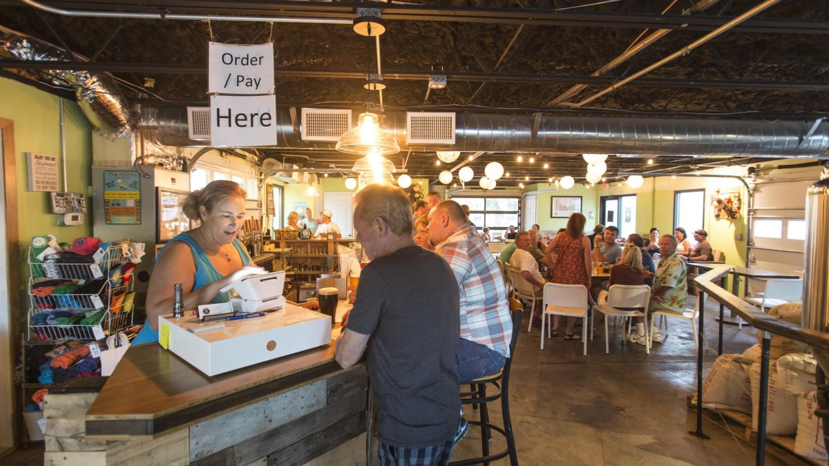 Two man at the cashier and several people dining at the Cueni Brewing Co.