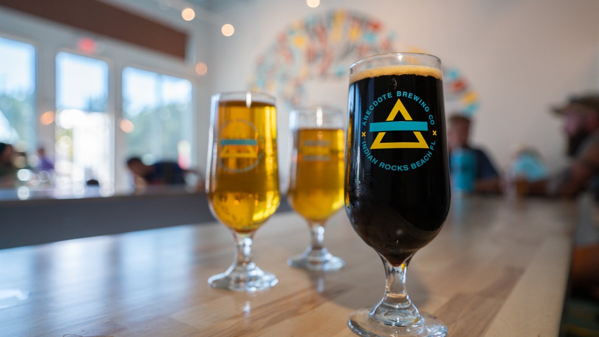 One dark and two blonde beer glasses on top of a wooden bar.