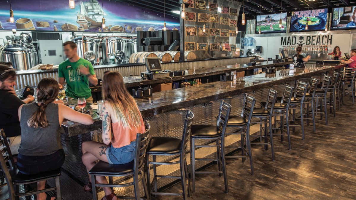 A few people sit at the bar at Mad Beach Brewing.