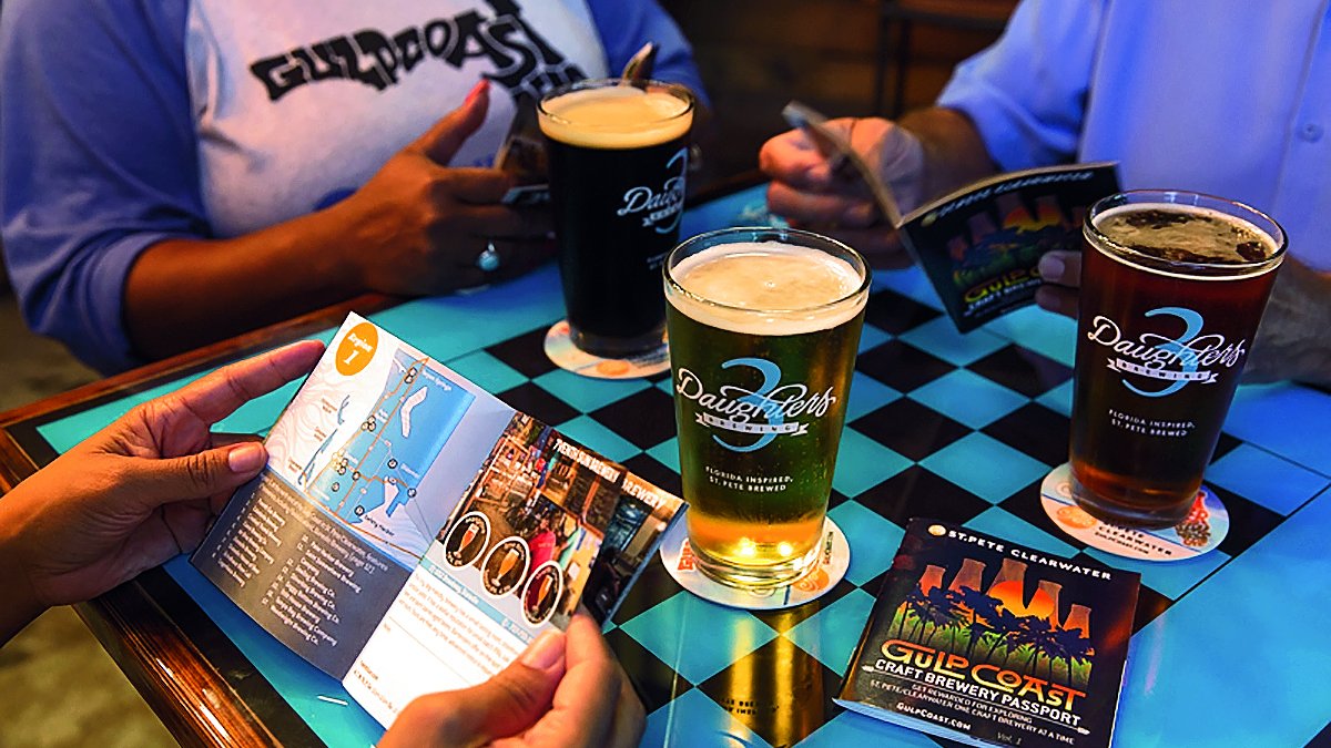 A group of people enjoying beers and reading through the craft beer passport connecting all breweries in Pinellas County.