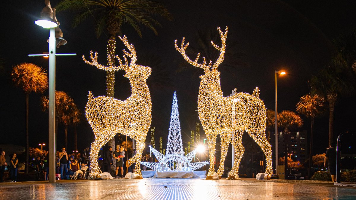 Two reindeer light statues with a Christmas light tree behind