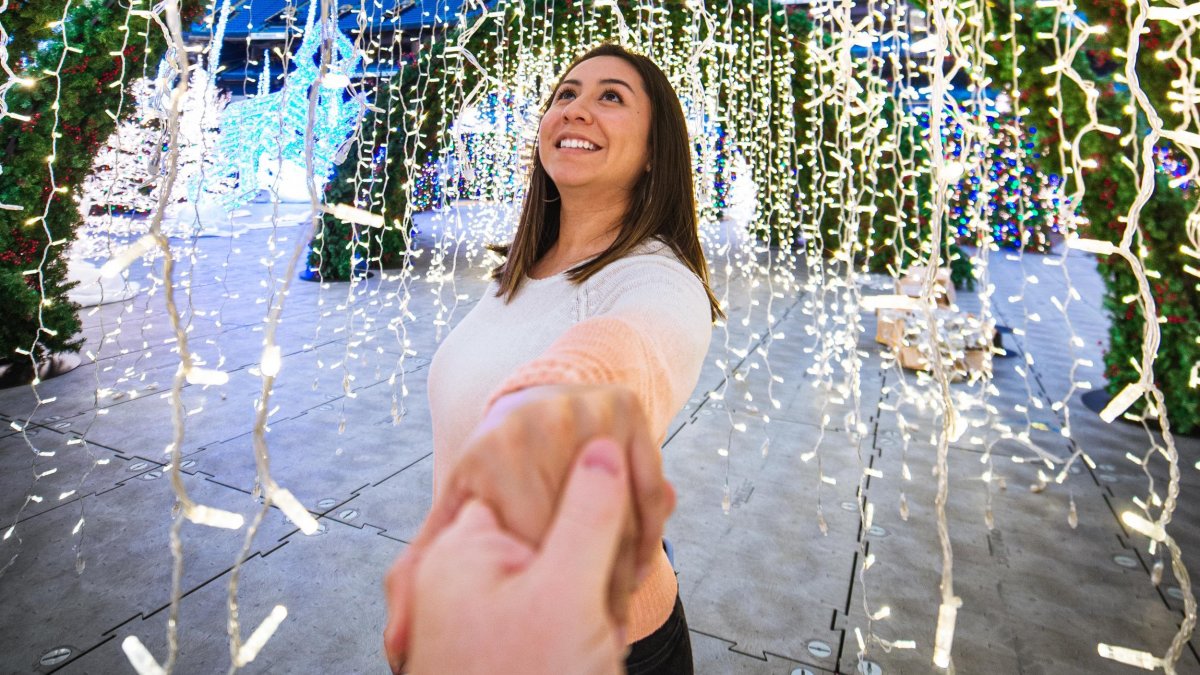 A woman looks at Christmas lights while holding someone's hand