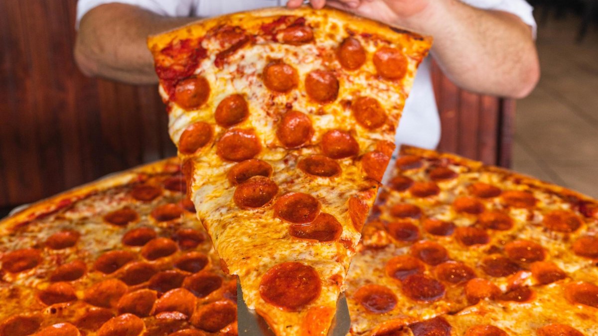 A man holds up a slice of pepperoni from Madison Avenue Pizza
