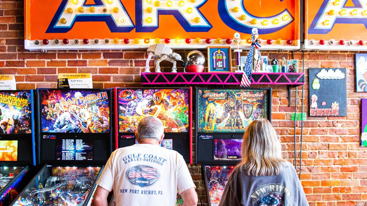 Two people play pin ball at the Replay Museum