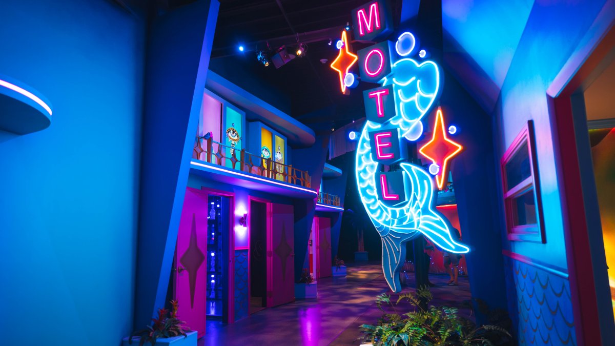 A neon sign outside an artistic replica of a vintage Florida hotel