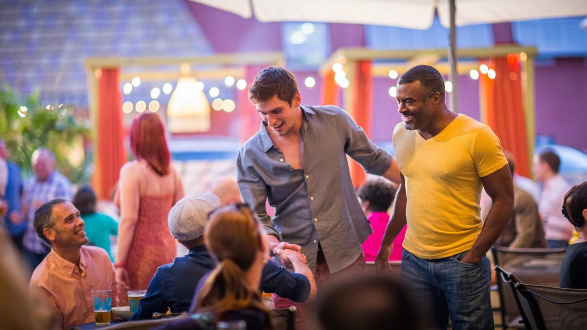 A couple men greet friends at a LGBT+ Bar and Restaurant