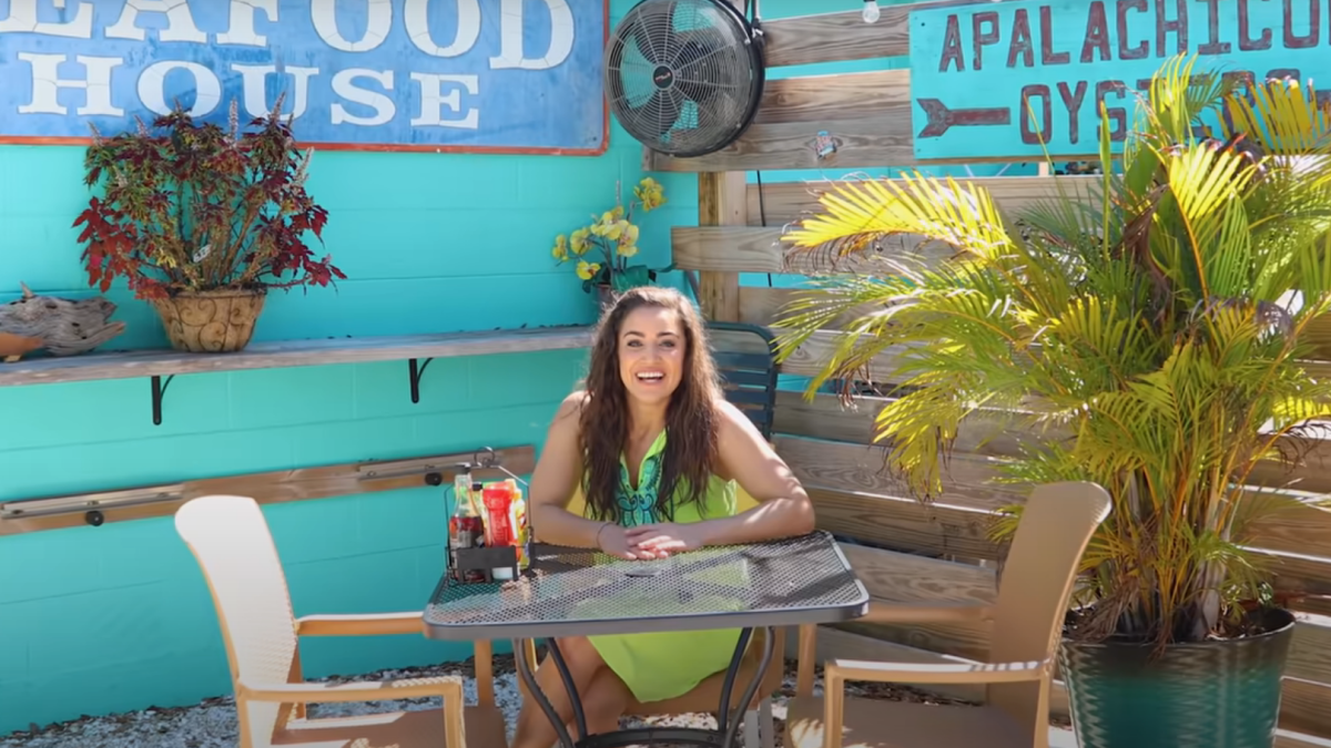 A woman sits at a table outside Hog Island Fish Camp