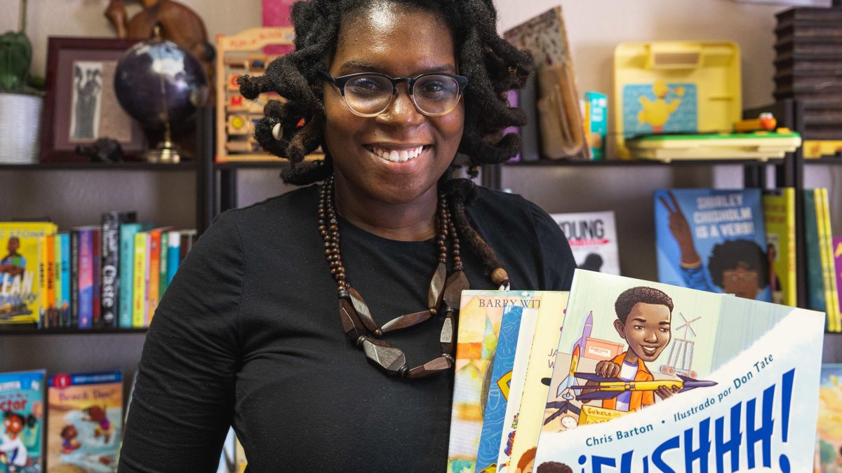 A woman holds up a book from the book store she owns.