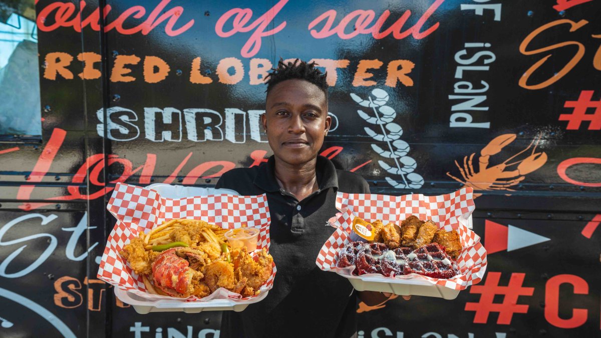 A young woman holds up two dishes from her food truck.