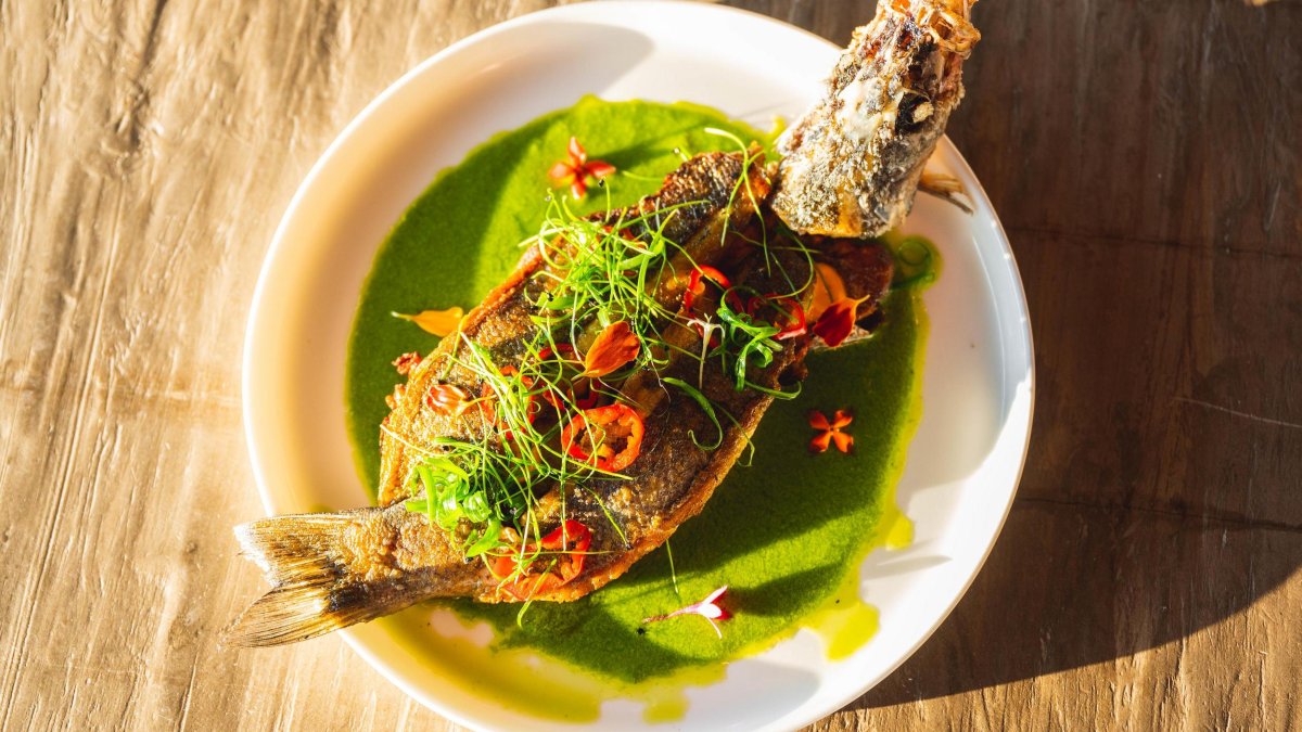 A crispy whole fish served in a dish with a green curry sauce at Sea Worth Fish + Bar in Tierra Verde