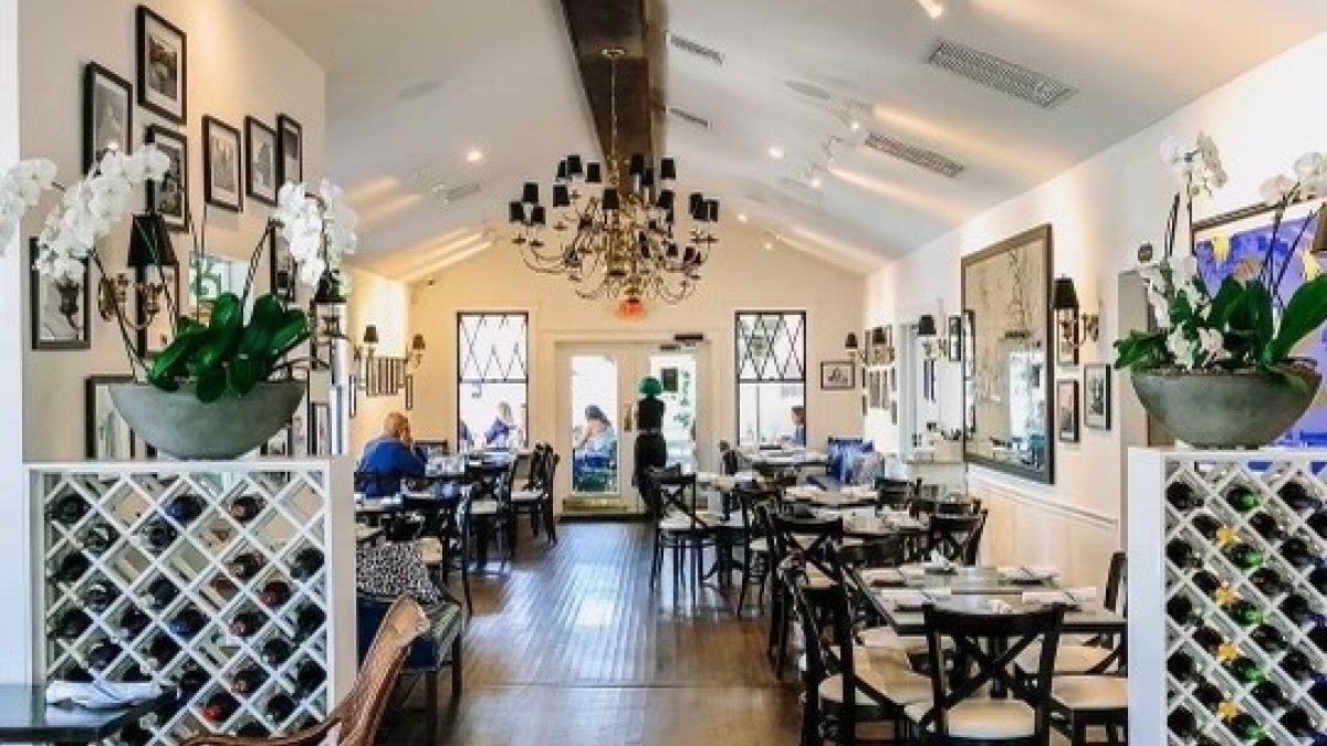 interior of Left Bank Bistro French restaurant in a historic bungalow with chandelier, leopard print chair and tables in background