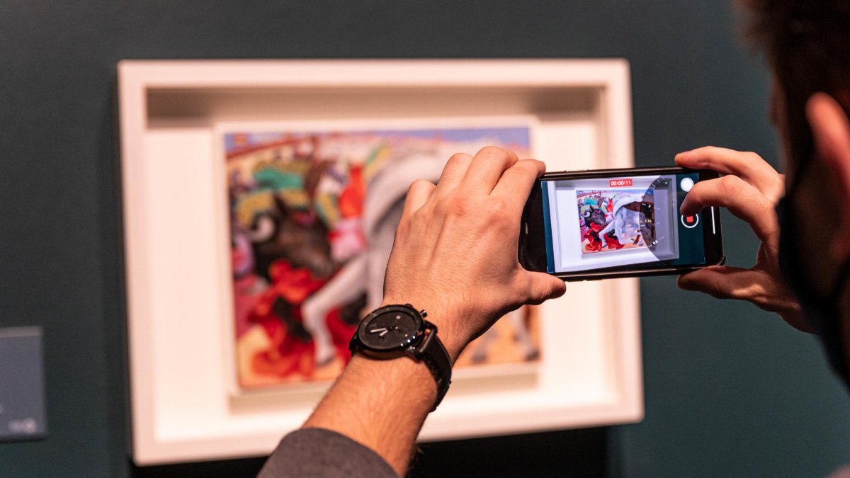 A museum guest takes a photo of a painting at the Dali Museum during the Picasso exhibit.