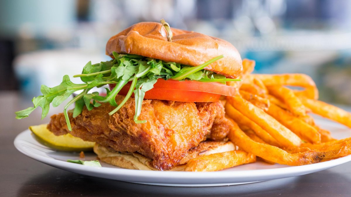 ein im Bierteig frittiertes Zackenbarsch-Sandwich mit Salat und Tomaten und Pommes als Beilage