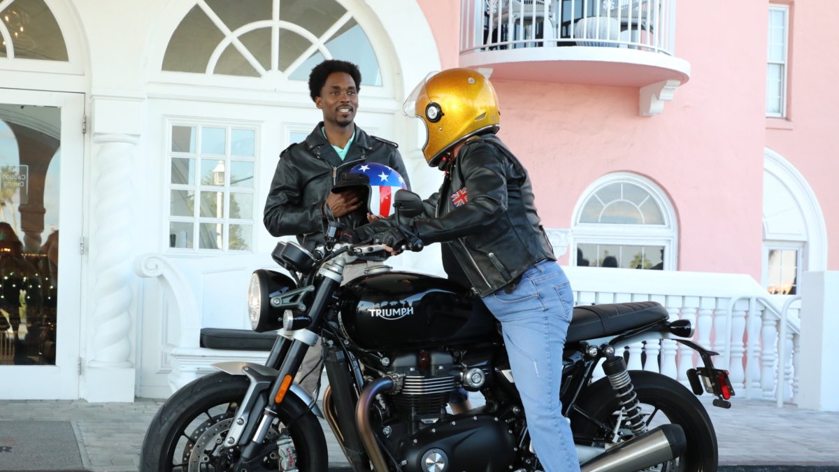 Man and motorcyclist talking outside the front doors of the lobby to the pink Don CeSar hotel on St. Pete beach. 