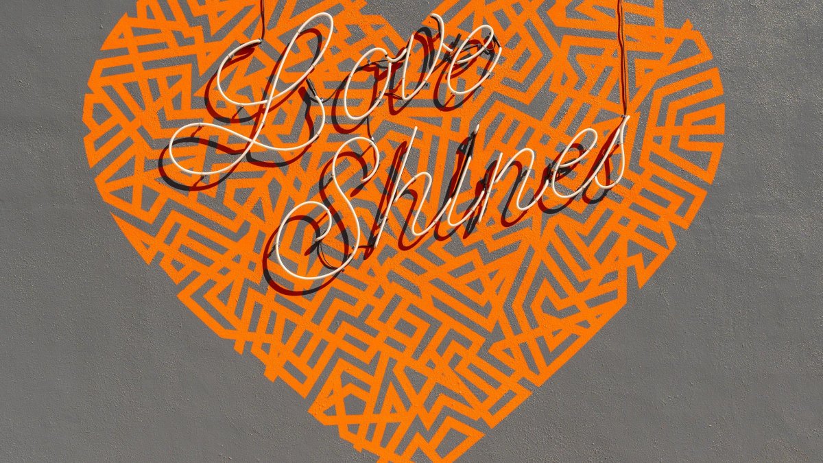 an orange heart-shape mural on a gray background says Love Shines in cursive script