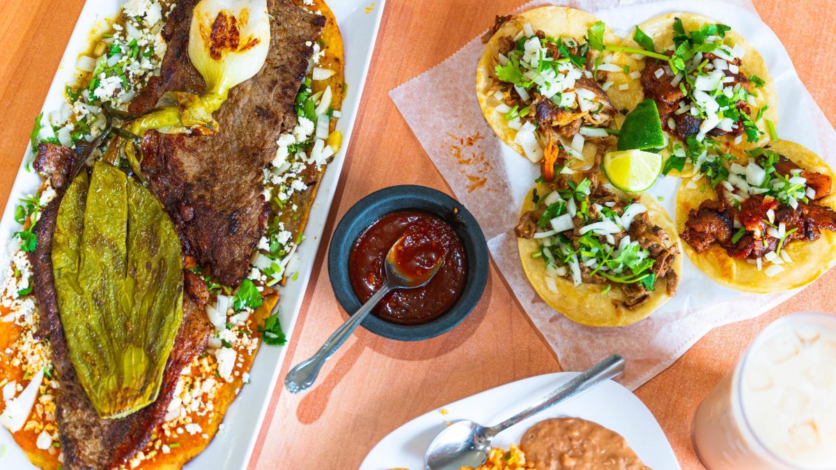 Colorful tacos on a plate next to a skirt steak with a green adobo pepper at El Huarache Veloz mexican restaurant in Pinellas Park