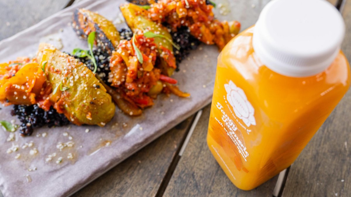 A fresh orange juice and a colorful plate of plant-based foods at Karma Juice Bar