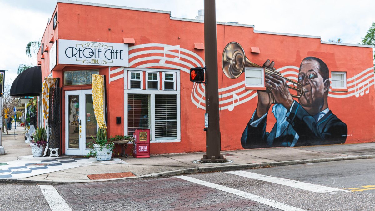 a mural on a red background depicts Louis Armstrong playing the trumpet with a white musical score and notes in the background