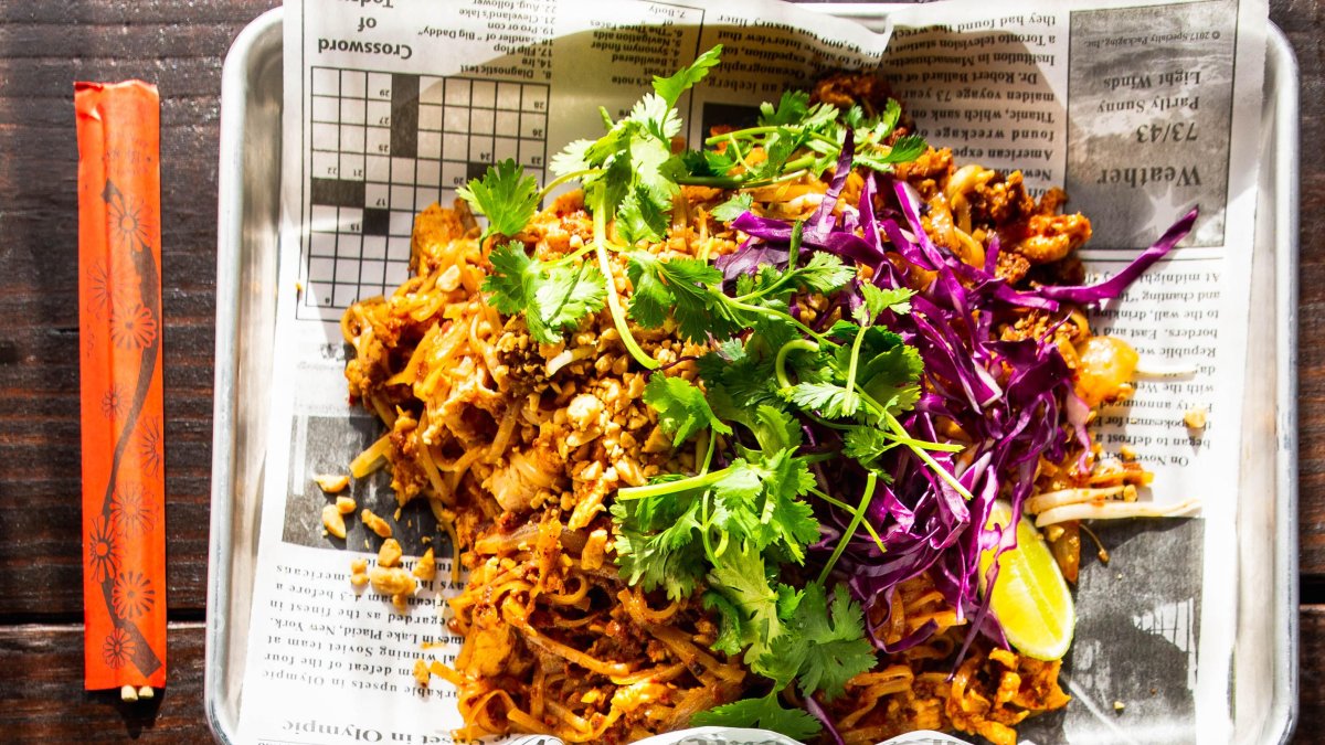 a plate of shredded pork or chicken decorated with cilantro and served on newspaper