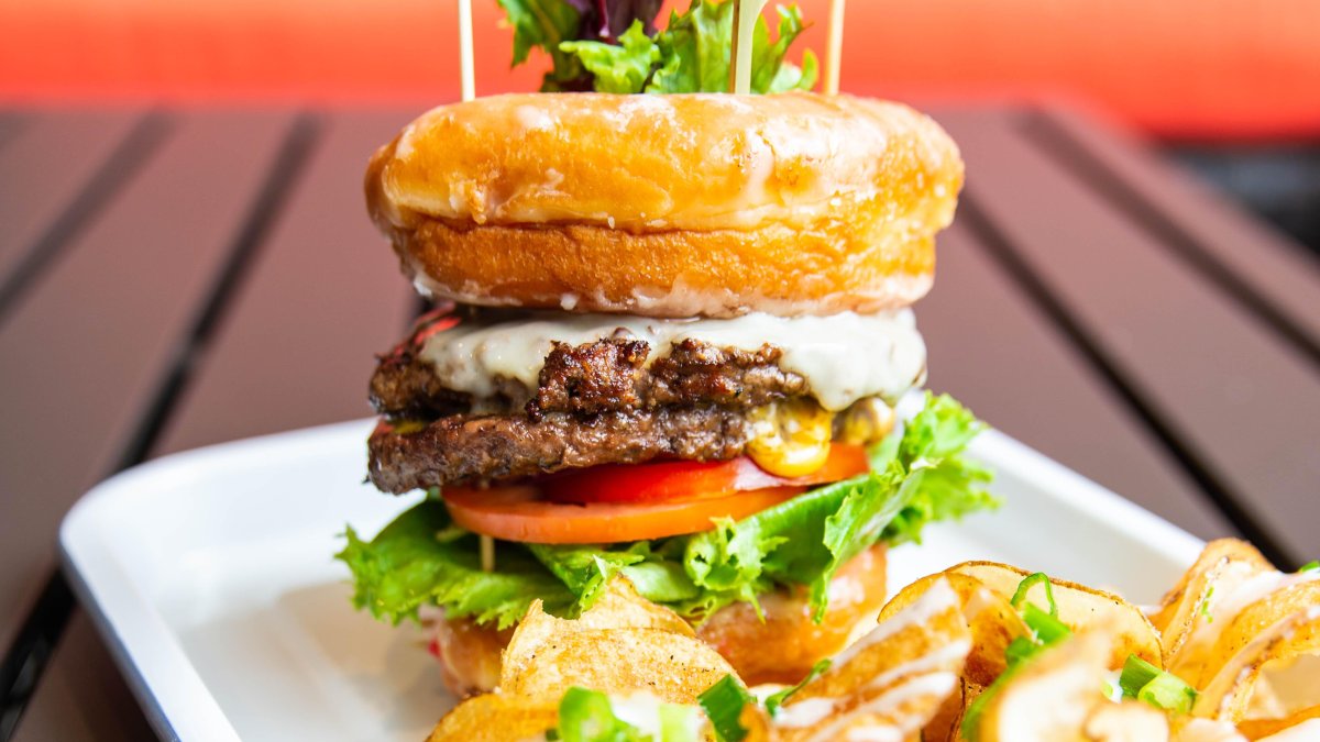 a double-decker burger with provolone cheese tomato and lettuce on a brioche bun with fresh chips at Datz in St. Pete