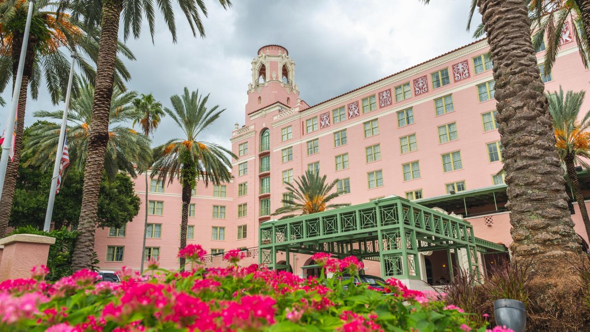 magenta and light pink zinnia flowers and two palm trees accent the large pink historic hotel the Vinoy Renaissance