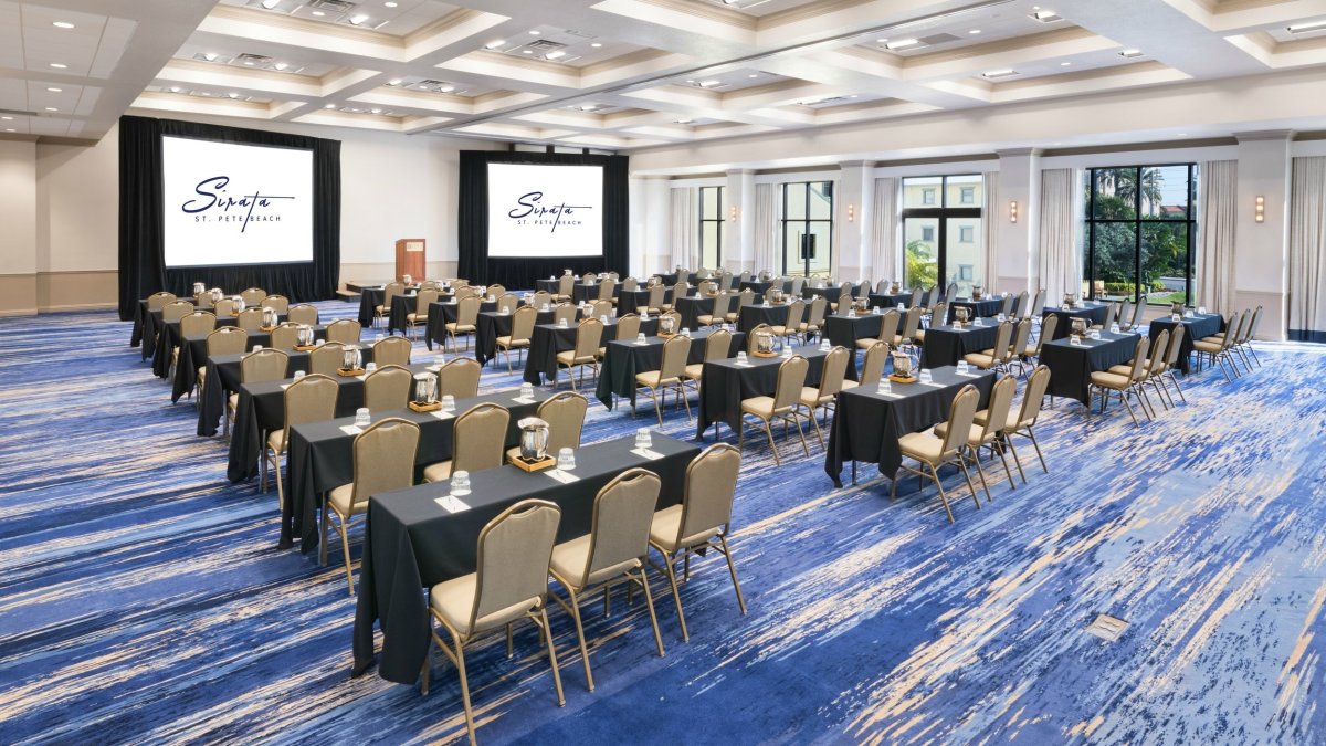 A room with chairs and tables facing two screens.