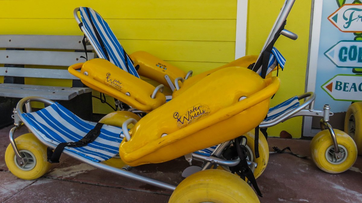 a bright yellow beach wheelchair that is styled like a lounge chair