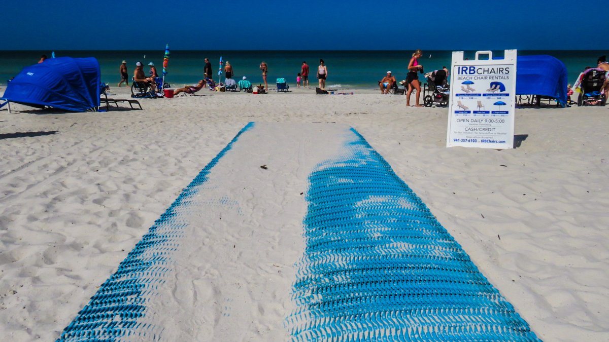 Eine leuchtend blaue Mobi-Mat mit Sand darauf erstreckt sich am Indian Rocks Beach in Richtung Golf