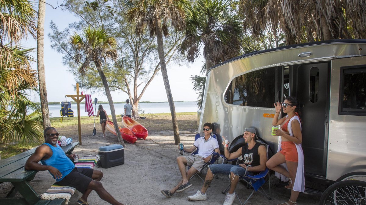 Friends sitting near a small RV at campground near the water at Fort DeSoto.