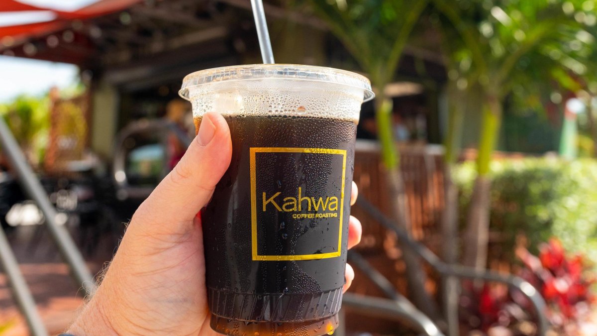 Hand holding a cup of iced coffee with Kahwa logo on it