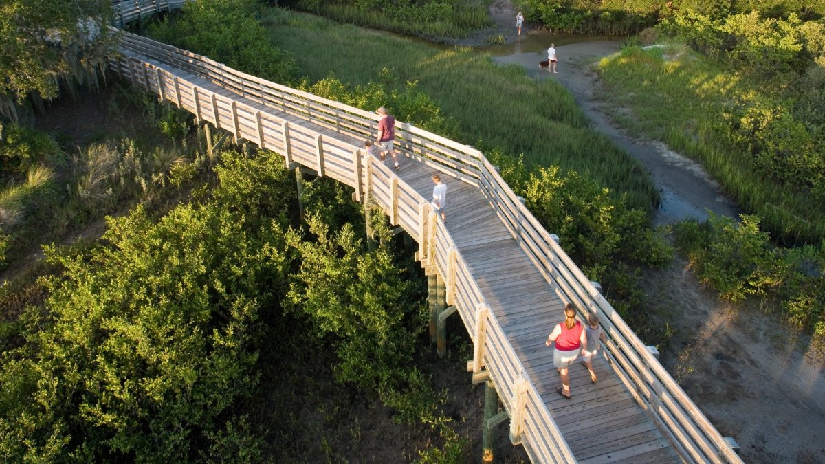 People stroll along a wooden boardwalk in Boca Ciega Millennium Park