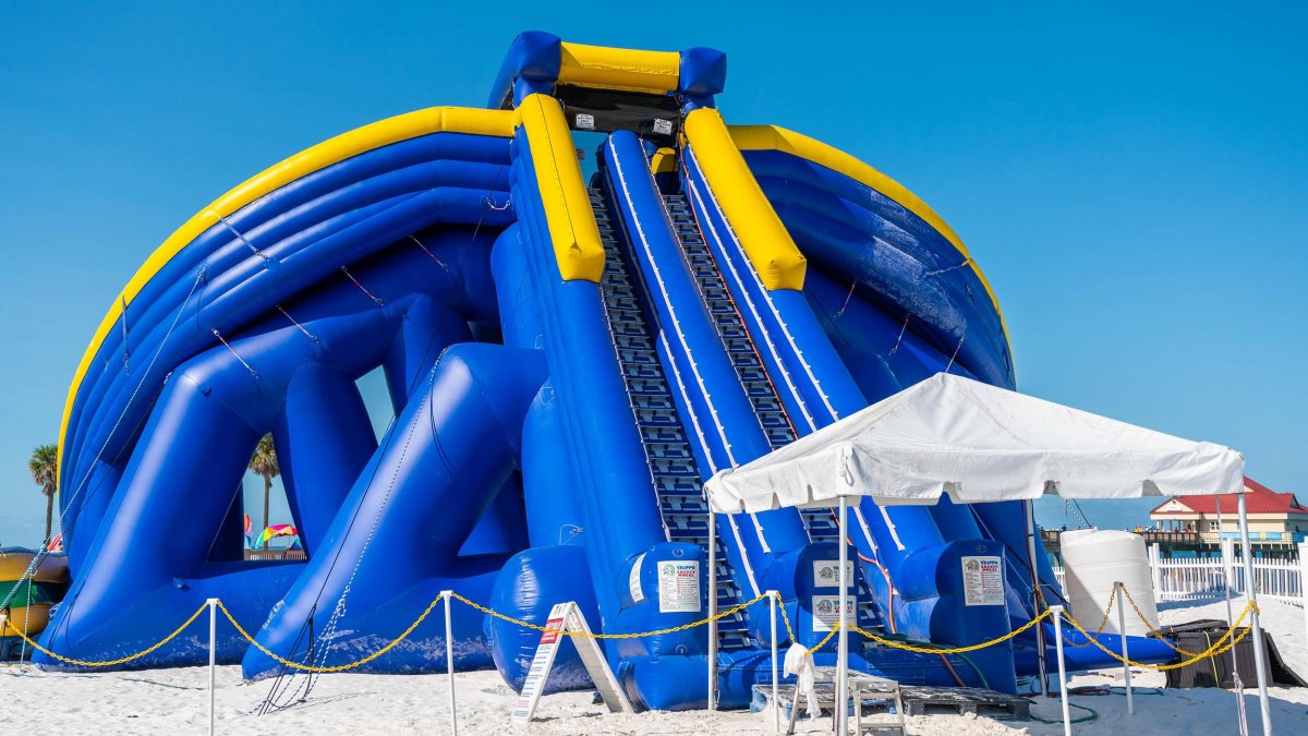 a huge blue and yellow inflatable slide on Clearwater Beach with a shaded canopy in front of it