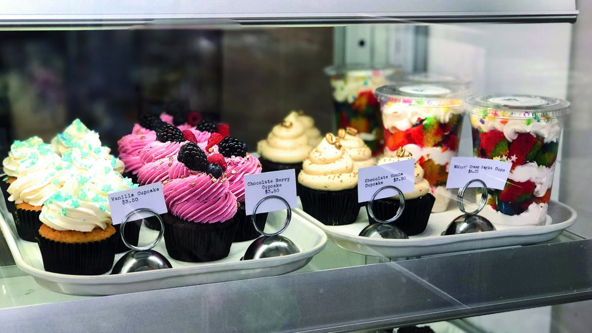 Colorful vegan cupcakes sit in a bakery case