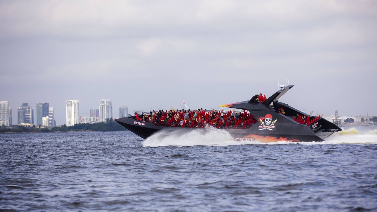 People with their hands up riding on the water in the Tampa Bay Rocket speed boat.