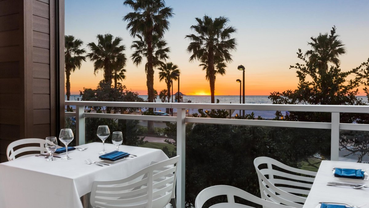 white chairs and a table with a white table cloth at Ocean Hai restaurant overlook sunset at the beach