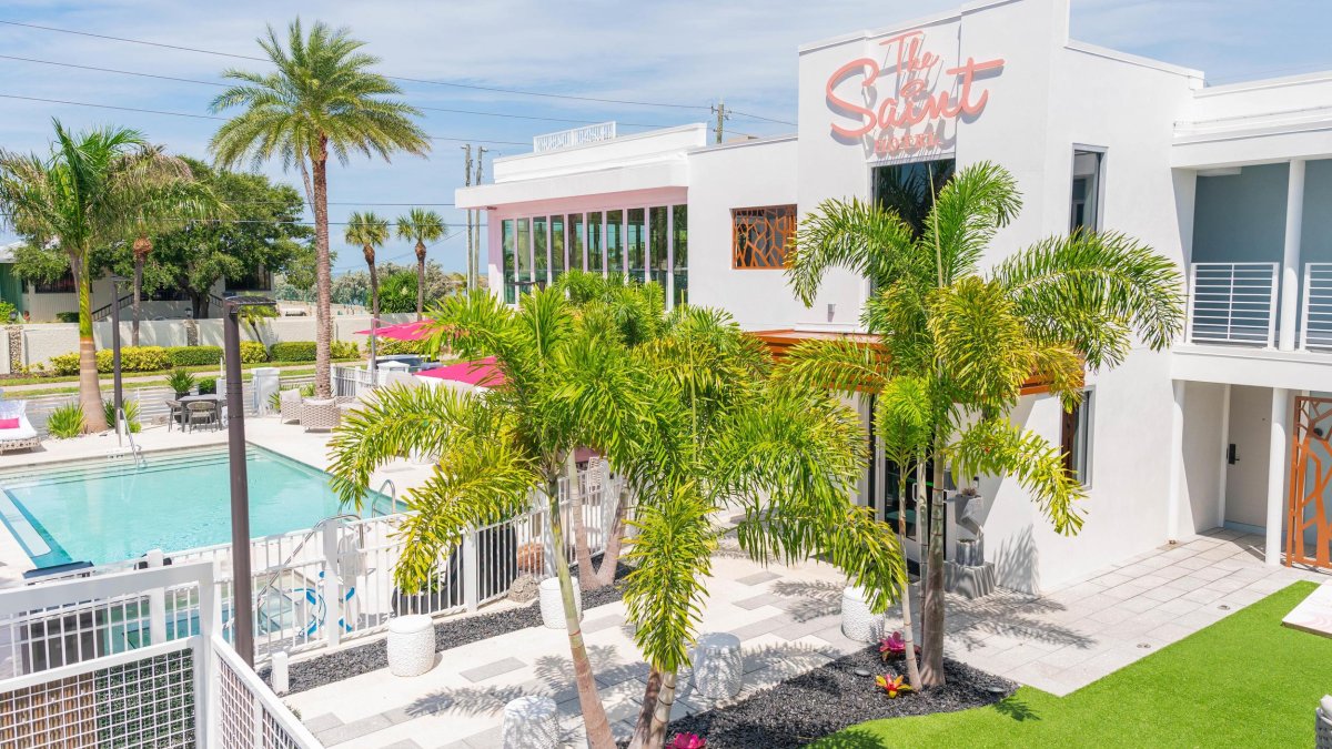 The exterior of the Saint Hotel in St. Pete Beach with palm trees, a lawn and pool