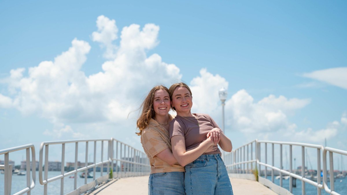 two women embrace and pose for the camera on the waterfront in Gulfport FL