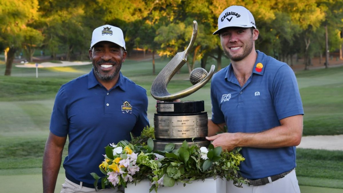 Two golfers holding a trophy at the PGA Valspar Championship.