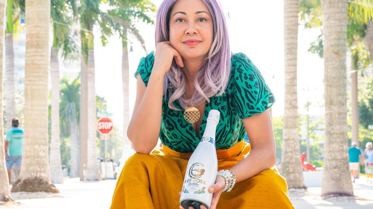 Woman with purple hair holds bottle of wine