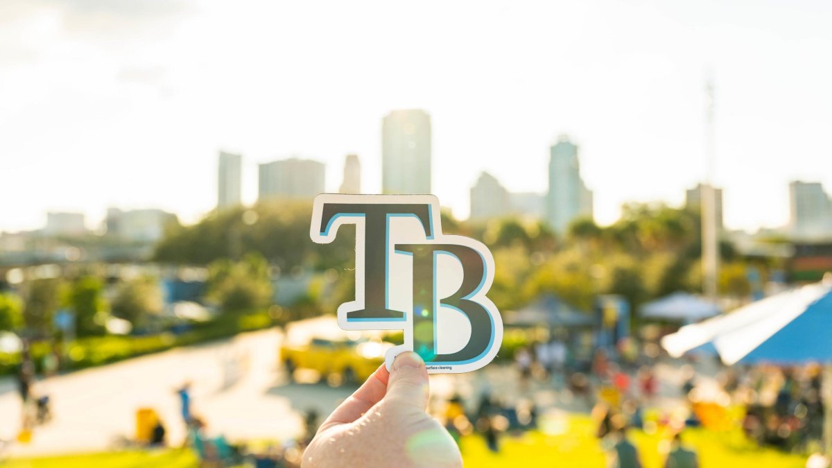 Tampa Bay Rays logo held up against St. Pete skyline