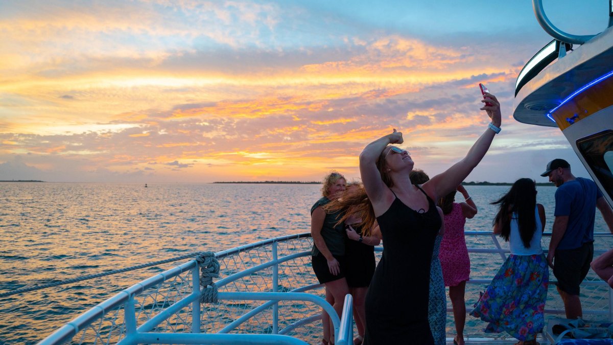 Woman taking a selfie aboard a sightseeing boat at sunset