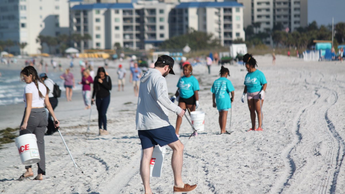 People clean up trash on the beach