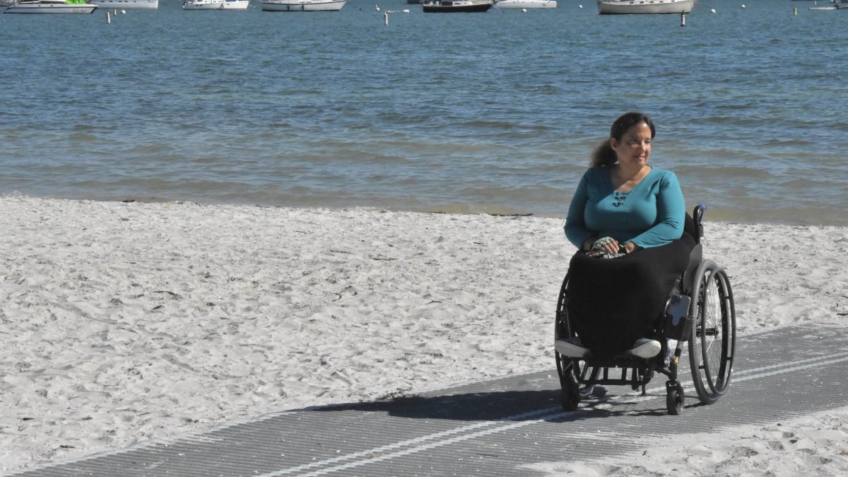 Frau im Rollstuhl auf Mob-Mat am Strand