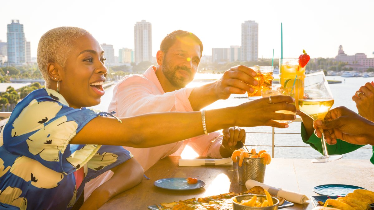a group of friends toasting with drinks at Pier Teaki at the St. Pete Pier