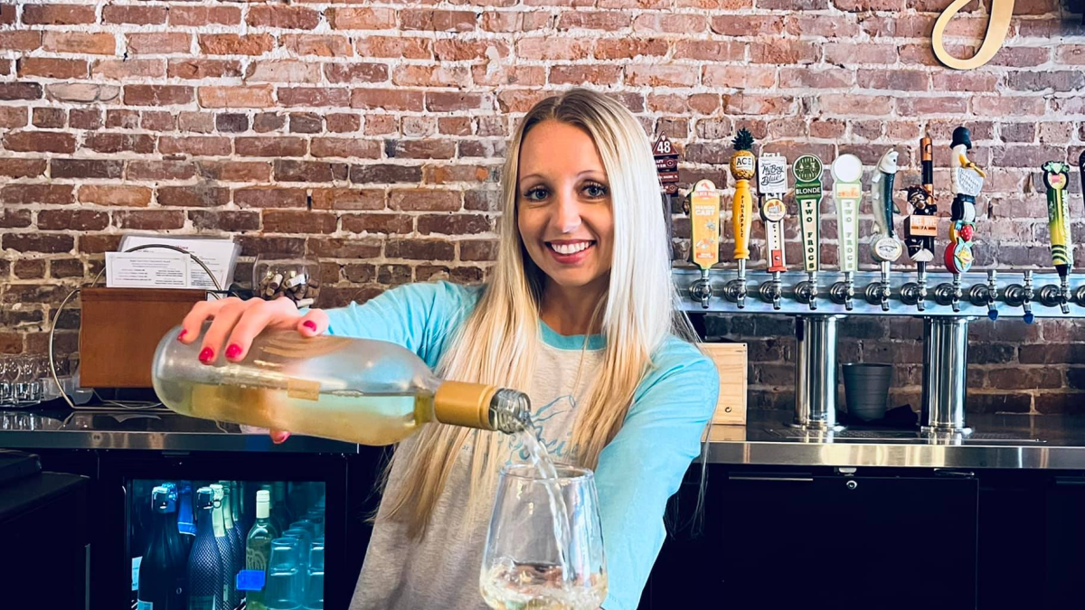 Woman pouring white wine at Wine Society, Tarpon Springs