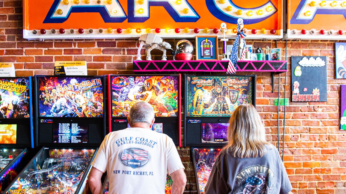 Un hombre y una mujer juegan máquinas de pinball en el Museo Replay en Tarpon Springs, FL.