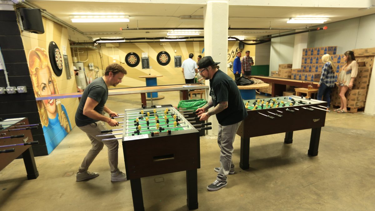 Young adults play foosball in the game room at a brewery.